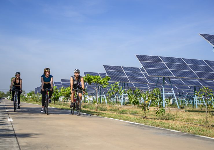 People are exercising near solar powerplant. Work out and environment.